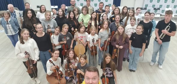 Na zdjęciu widać grupę młodych muzykant&oacute;w pozujących do zdjęcia w&nbsp;raz z&nbsp;skrzypcami