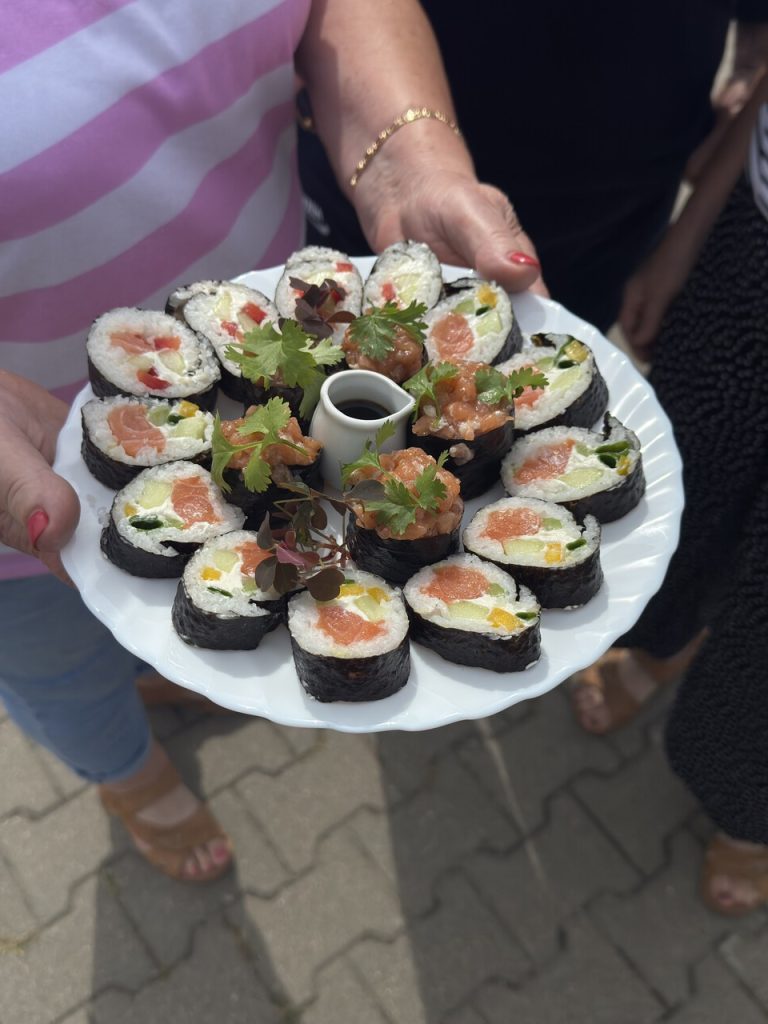Talerz sushi z&nbsp;r&oacute;żnorodnymi składnikami, podany z&nbsp;sosem sojowym i&nbsp;świeżymi ziołami.