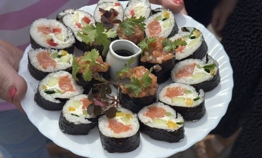 Talerz sushi z różnorodnymi składnikami, podany z sosem sojowym i świeżymi ziołami.