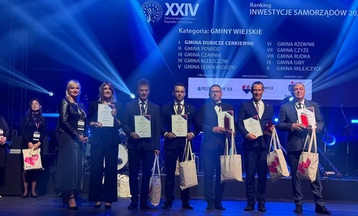 Na zdjęciu widać laureatów rankingu inwestycyjnym „Wspólnoty”. trzymaj oni dyplomy i statułetki. wszyskto jest podświetlone na niebiesko 